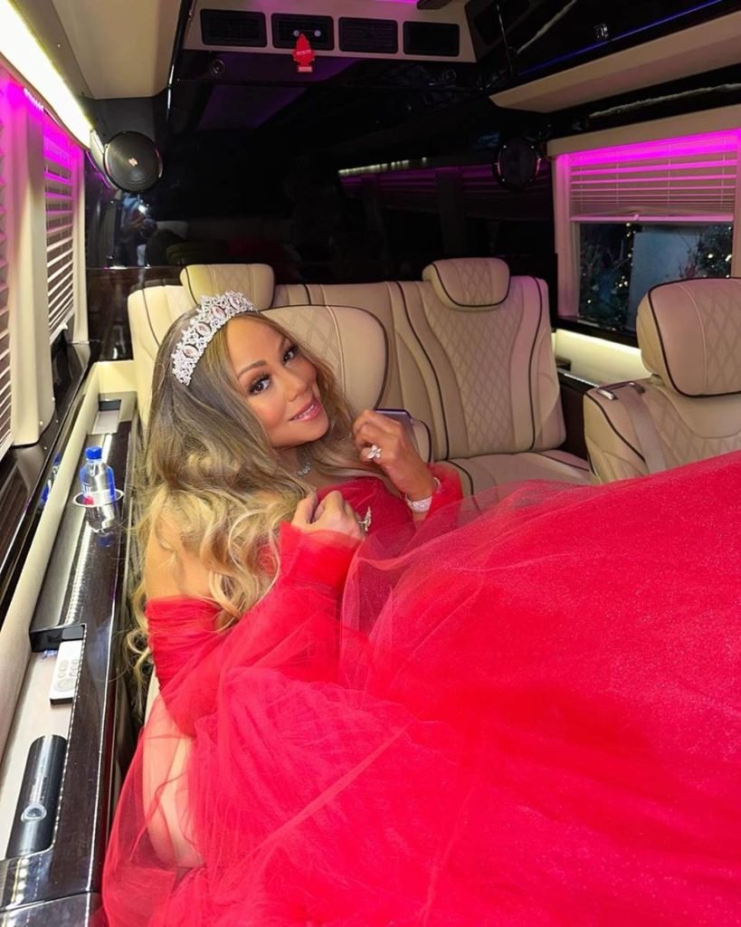 Mariah Carey de vestido vermelho deitada em banco de carro - metrópoles