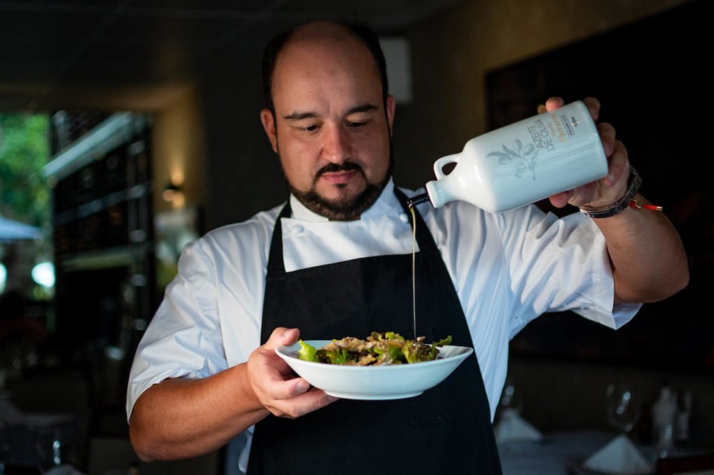 Na foto, o chef Marcelo Petrarca joga azeite em um prato de salada - Metrópoles