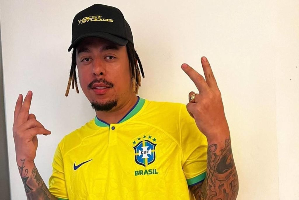 WC no Beat de blusa do brasil e boné fazendo V de vitória com dedos - metrópoles