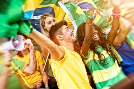 Foto colorida: torcedores com a camisa do Brasil abraçados na Copa do Mundo - Metrópoles