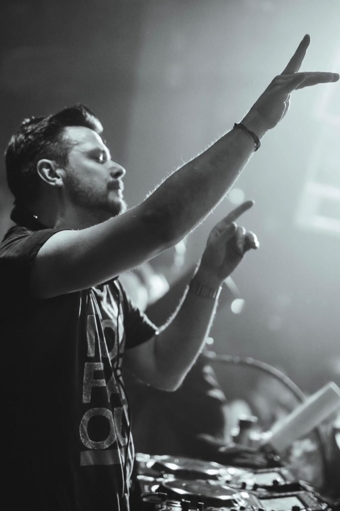 Imagem em preto e branco: DJ ATB de perfil com as mãos levantadas