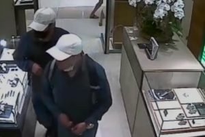 Imagem colorida: dois homens de boné caminham em joalheria - Metrópoles
