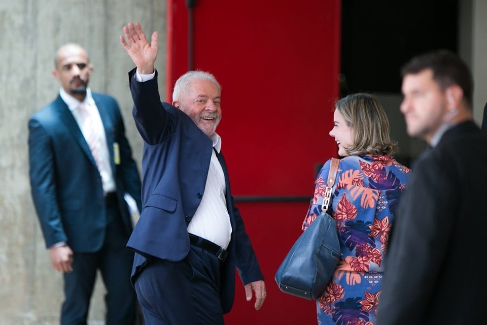 Lula chegando ao CCBB para reuniões da equipe de transição. Ele acena para a imprensa e a presidente do PT, Gleisi Hoffmann, sorri ao seu lado - Metrópoles