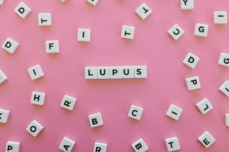 blocos de letras de jogo formando a palavra lúpus em fundo rosa