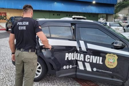 Agente da polícia civil do estado de santa catarina aparece abrindo a porta traseira de uma viatura - Metrópoles