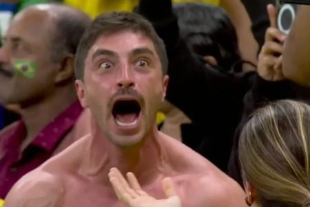 Homem branco e sem camisa gritando durante jogo do Brasil na Copa do Mundo
