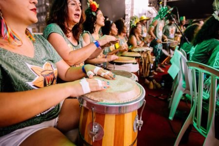 fileira de mulheres sentadas tocando tambores