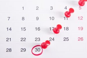 Imagem mostra representação de uma calendário de um mês de trinta dias, em que o último dia está marcado de vermelho. Há alfinetes | Metrópoles