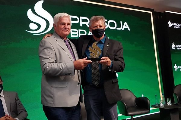 Ricardo Galvan e Bartolomeu Braz, dirigentes da Aprosoja, posam para foto segurando um troféu