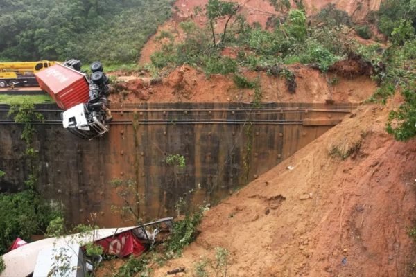 Imagem colorida mostra um caminhão vermelho despencando de uma estrada após deslizamento de terra no Paraná - Metrópoles