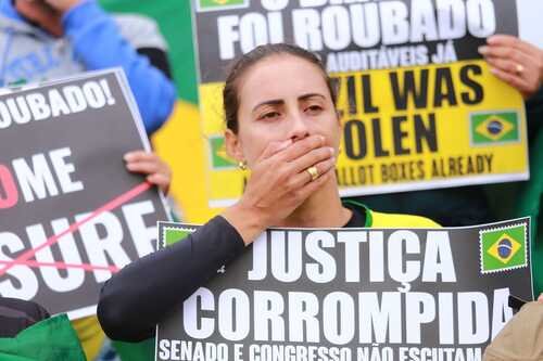 Manifestantes bolsonaristas participam de protesto golpista em frente ao QG do Exército, em Brasília, pedindo intervenção militar. Eles seguram cartazes afirmando que o