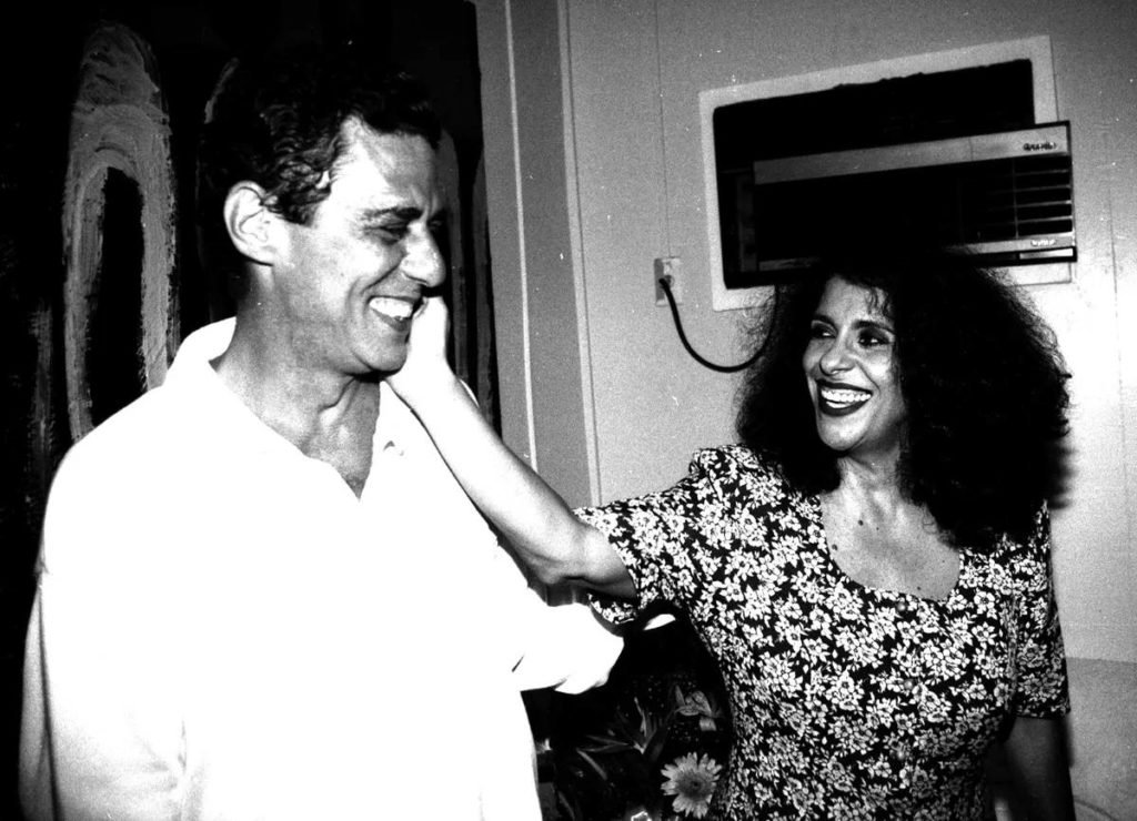 Chico Buarque e Gal Costa em backstage de show antigo, em imagem preta e branca. Ambos sorriem e se abraçam - Metrópoles