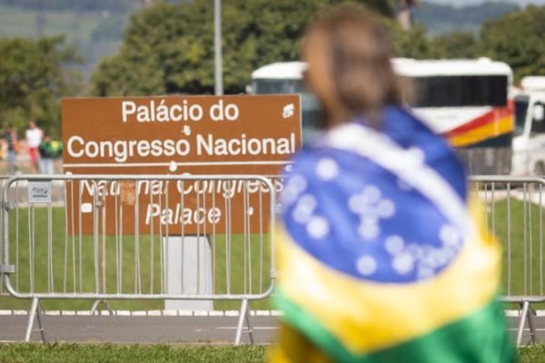 Apoiadora do governo bolsonaro, vestida com a bandeira do brasil, se concentra proximo ao congresso nacional durante ato bolsoanrista na esplanada ministerios - Metrópole