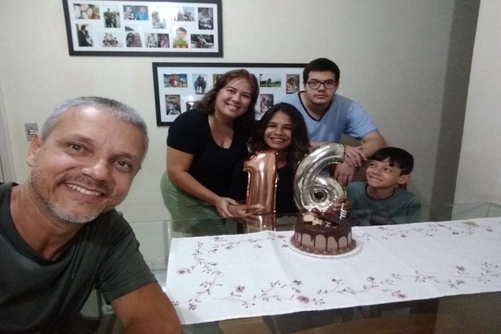 Foto de um homem na frente, uma mulher e três crianças atrás de uma mesa