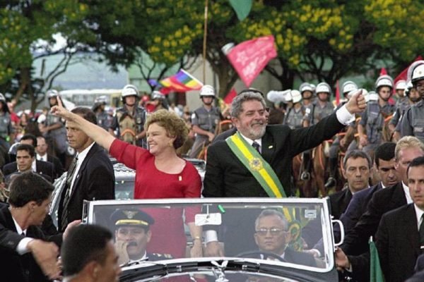 Foto colorida do presidente Lula da Silva e Marisa Letícia acenam para população no desfile pela Esplanada em 2003 - Metrópoles