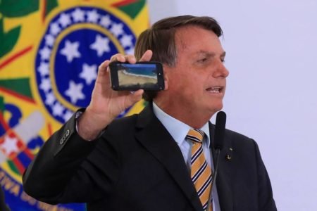 foto colorida dopresidente jair bolsonaro segurando um celular