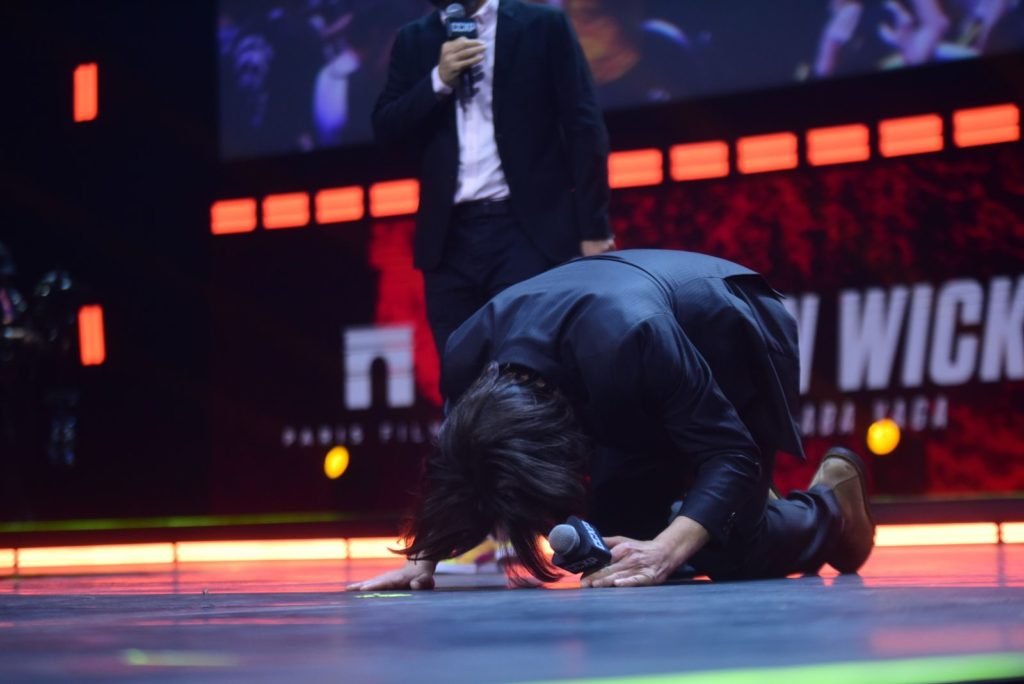 Keanu Reeves ajoelhando em cima do palco CCXP