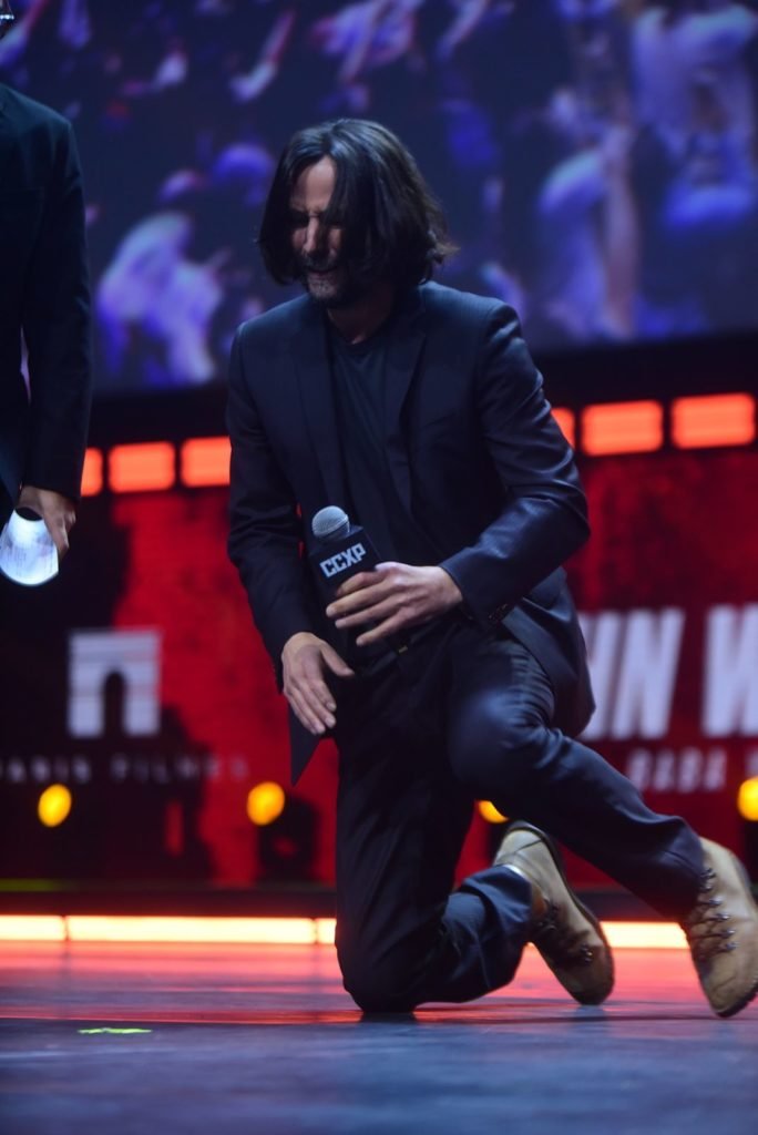 Keanu Reeves ajoelhando em cima do palco CCXP