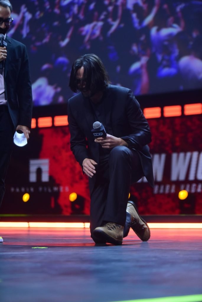 Keanu Reeves ajoelhando em cima do palco CCXP