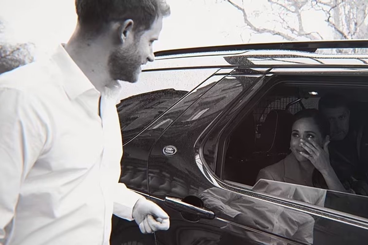 Foto em preto e branco de homem branco fora de um carro e uma mulher chorando dentro do veículo - Metrópoles