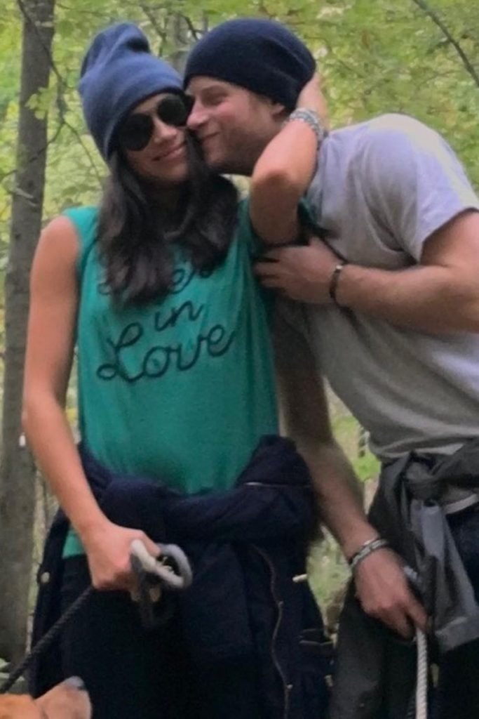 Foto colorida de mulher parda com touca e óculos escuro abraçada em homem branco e ruivo - Metrópoles