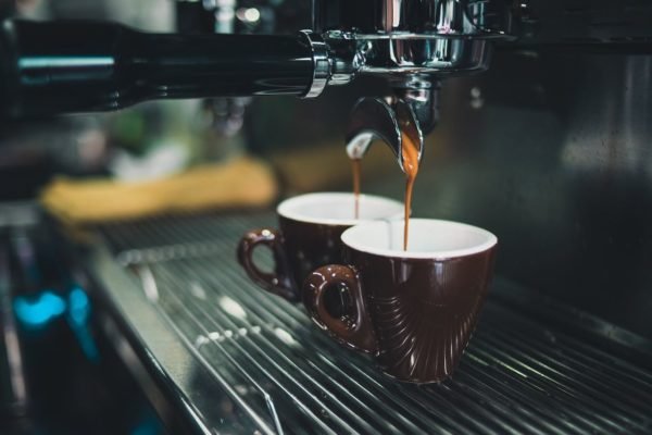 Na foto, dois cafés espressos sendo feitos em máquinas - Metrópoles