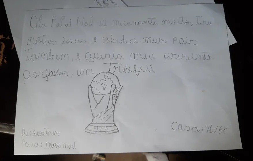 Foto de uma carta escrita por um criança de 10 anos a lápis. Além do pedido de um troféu, há um desenho representando a taça dada pela Fifa aos campões da Copa do Mundo