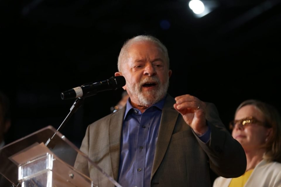 O presidente eleito Lula fala em coletiva de imprensa com membros da equipe de transição e apresenta alguns de seus ministros, no CCBB. Em destaque, ele gesticula diante de um púlpito - Metrópoles