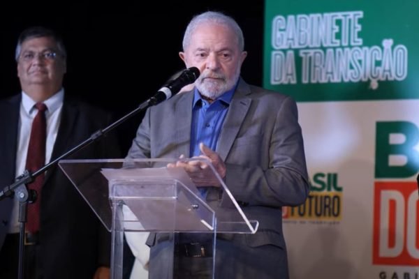 O presidente eleito Lula fala em coletiva de imprensa com membros da equipe de transição e apresenta alguns de seus ministros, no CCBB. Em destaque, ele gesticula diante de um púlpito - Metrópoles