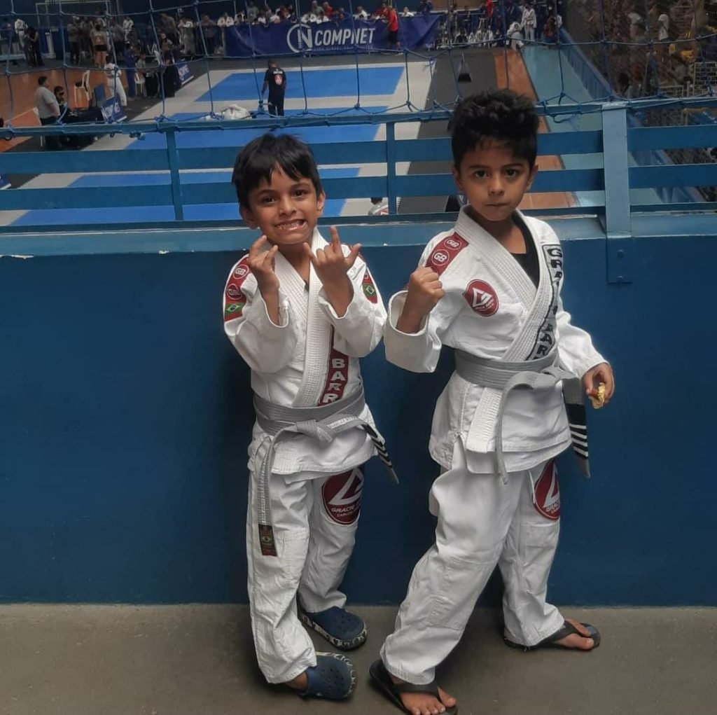 Dois meninos pequenos com roupão de luta em ginásio