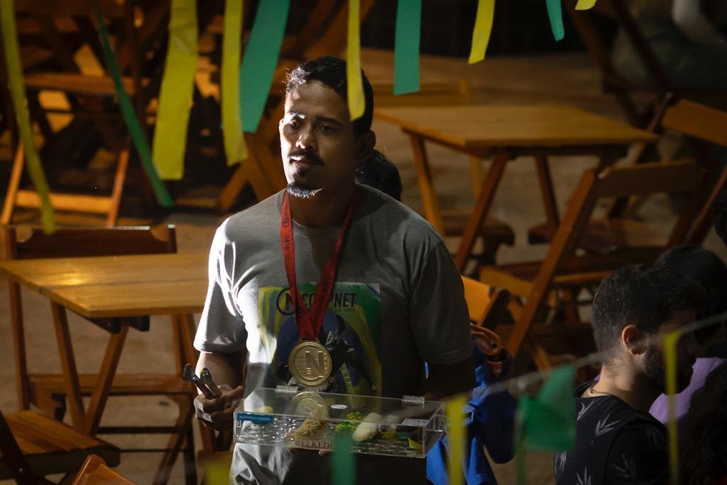 Homem com medalha no pescoço caminha em bar