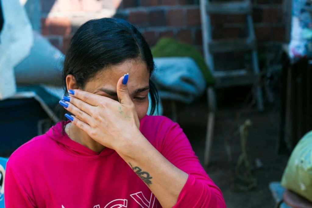 Mulher de camisa rosa seca lágrimas com a mão