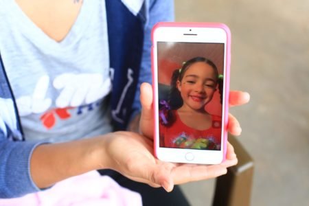 Mulher segura celular com foto de criança