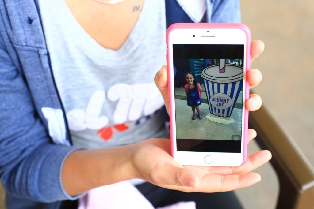 Mãe segura celular com foto de menina