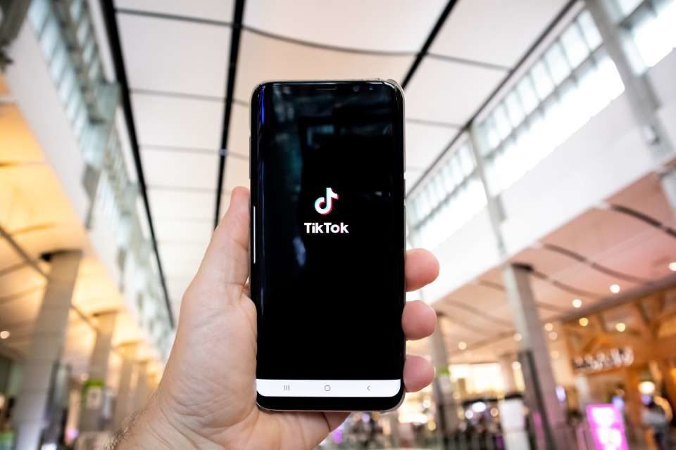 Na imagem, há um celular com uma imagem do TikTok