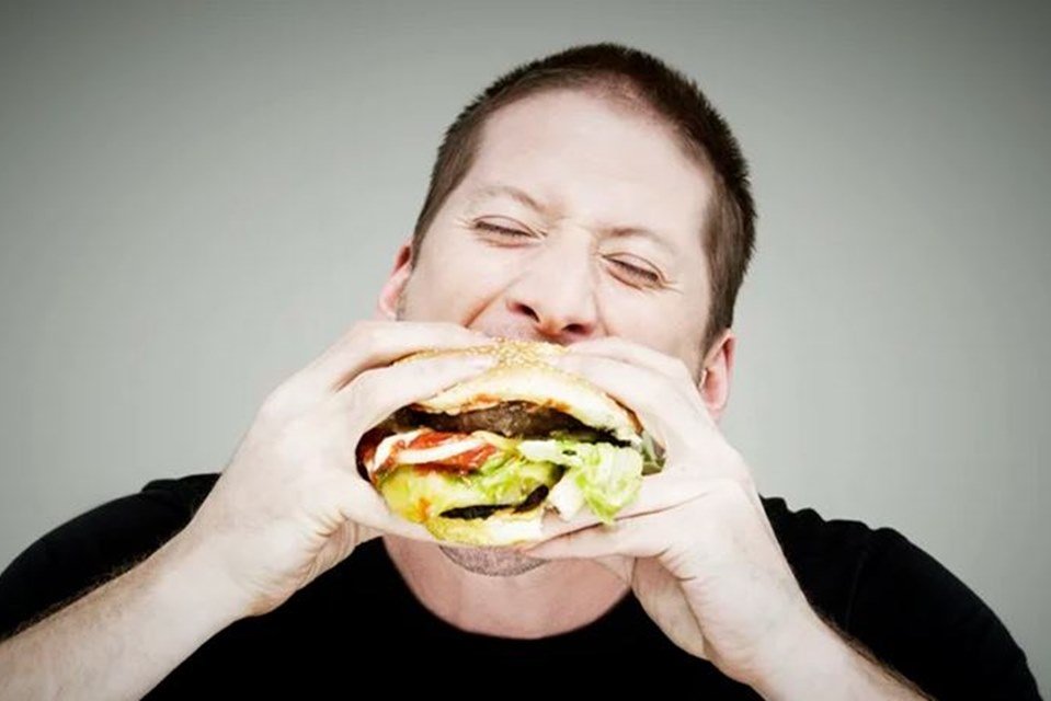 Homem comendo hambúrguer - Metrópoles