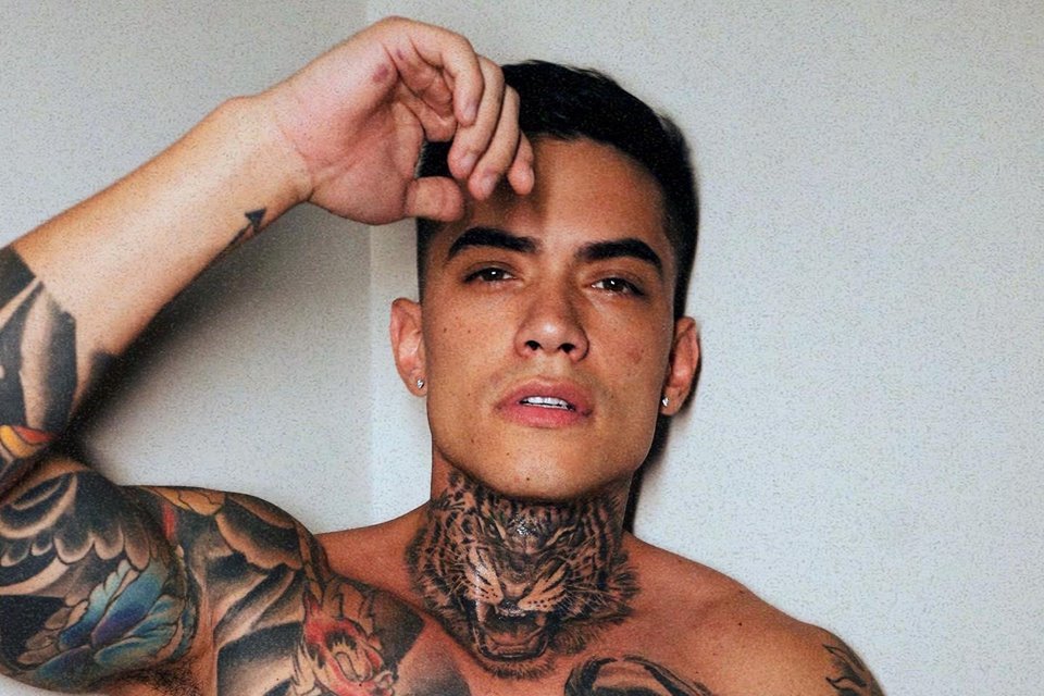 Foto colorida de Lincoln Lau. Ele é um homem de cabelo preto, pele clara, tatuagens no pescoço e no peito e está sem camisa - Metrópoles