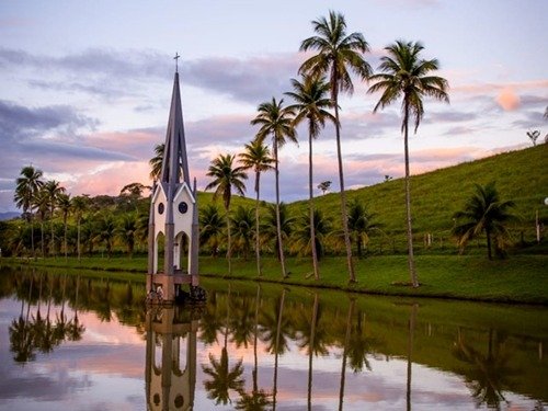 Lago refletindo palmeiras e uma igreja