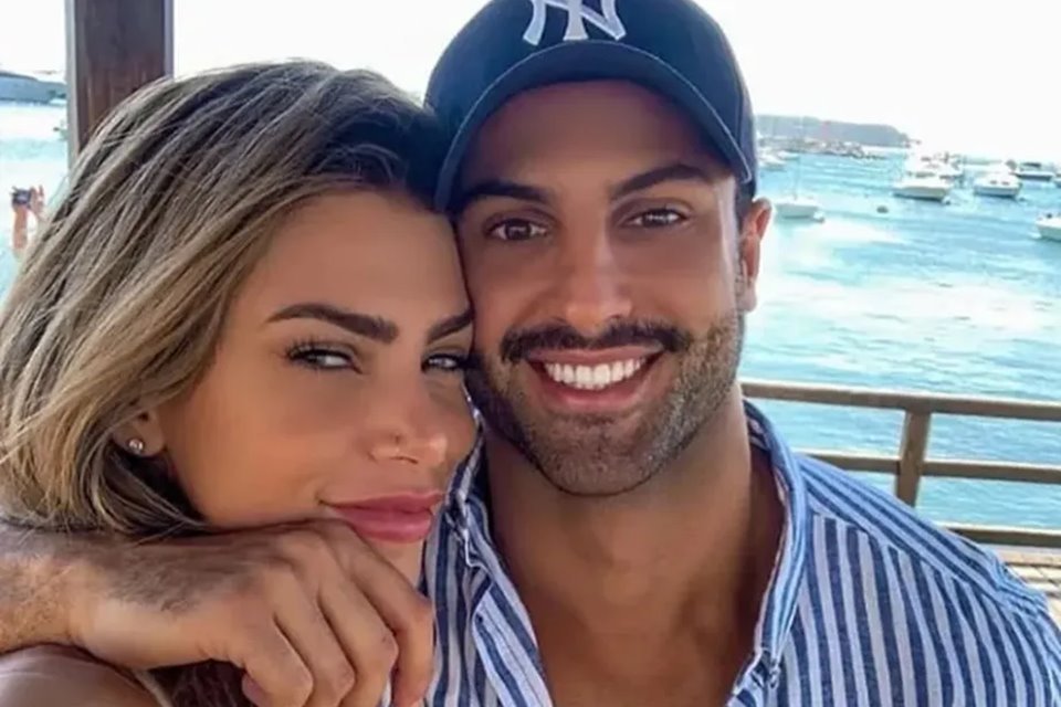 Foto colorida de Erika Schneider e Victor Peres. Ela é loira e está abraçada com ele, que usa boné azul e tem bigode grosso e barba rala - Metrópoles