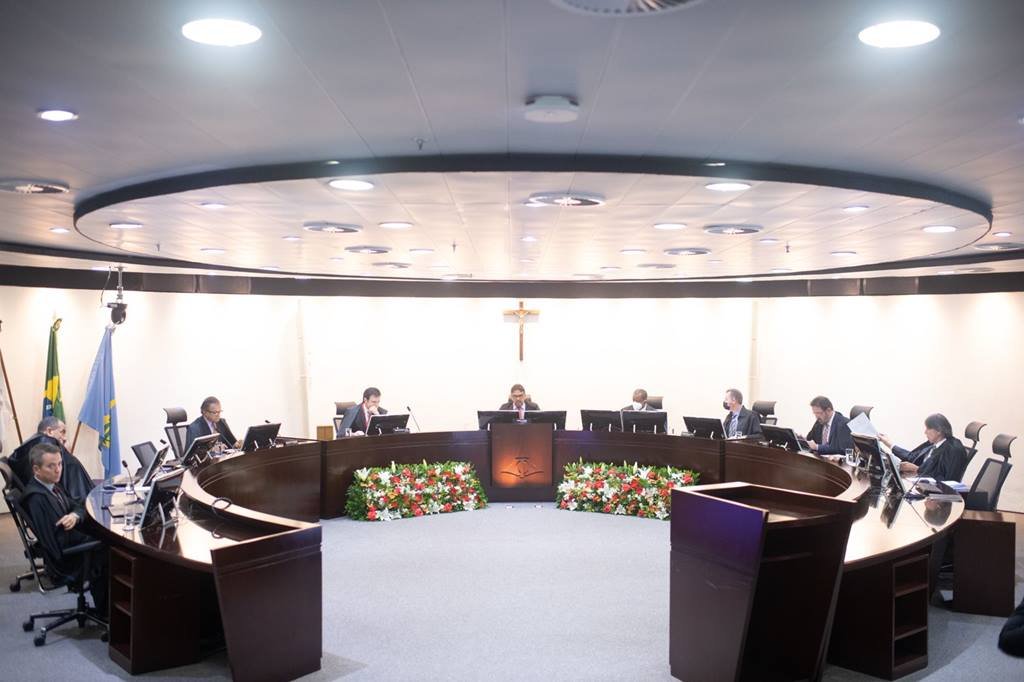 Sala com mesa redonda e pessoas sentadas ao redor