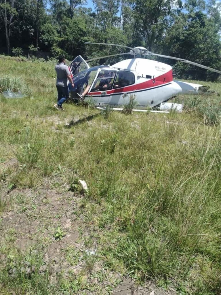 Helicóptero destruído após queda no Rio de Janeiro, em meio ao mato. Ele carragava cinco pessoas e na imagem é possível ver dois homens próximos dos destroços - Metrópoles