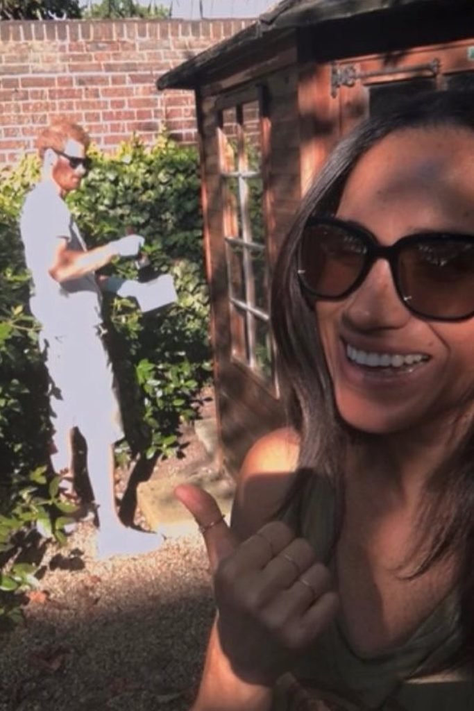Foto colorida de homem ruivo e branco ao fundo com mulher parda e sorridente fazendo selfie - Metrópoles