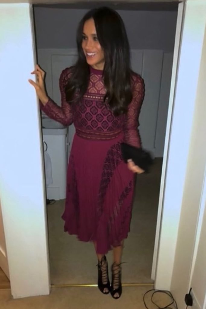 Foto colorida de mulher parda vestida com vestido na cor vermelha e bolsa nas mãos. Ela está escorada no portal de uma porta - Metrópoles