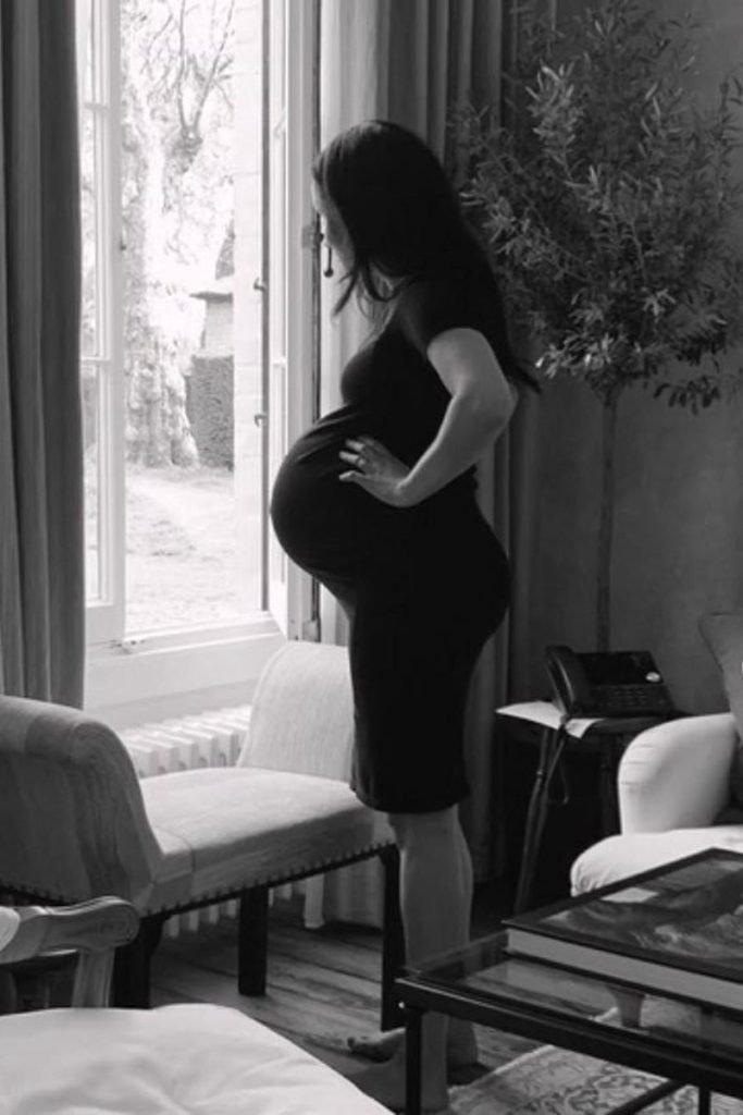 Foto em preto e branco de mulher grávida diante de uma janela - Metrópoles