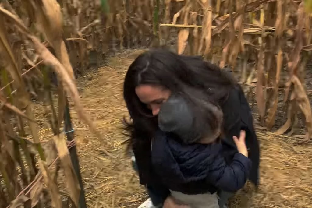 Foto colorida de menino abraçando mulher em meio a uma plantação - Metrópoles