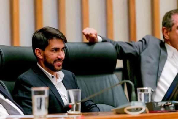O deputado distrital Cristiano Araújo durante sessão no plenário da Câmara Legislativa do DF. Ele está sentado na mesa da presidência e sorri - Metrópoles