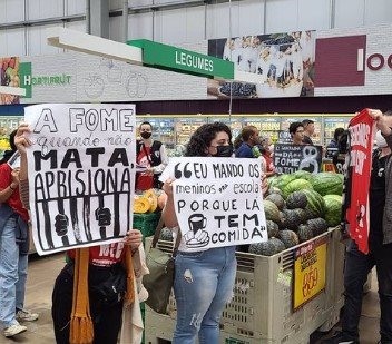 Pessoas seguram cartazes no supermercado