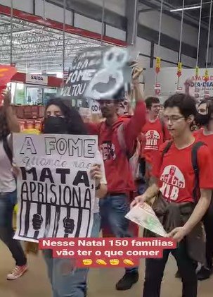 Pessoas de vermelho seguram cartazes e protestam no supermercado