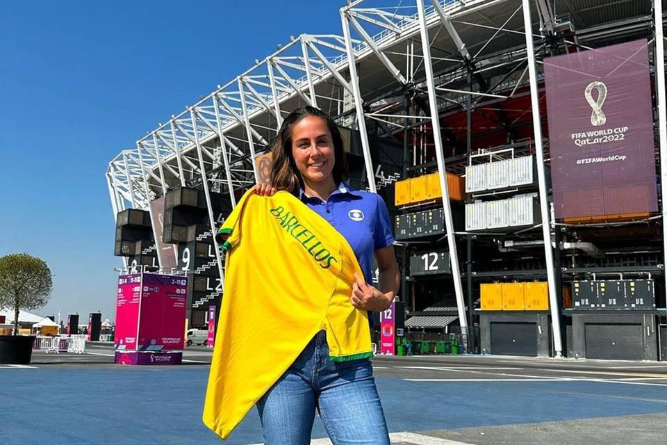 Carol Barcellos segura bandeira do Brasil em frente a estádio no Catar - metrópoles