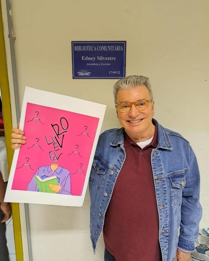 homem de cabelos brancos com jaqueta jeans segura imagem rosa com desenhos - metrópoles